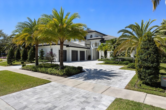 view of front of house with decorative driveway, an attached garage, and stucco siding