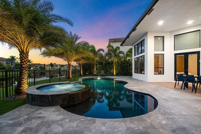 pool at dusk featuring a patio, fence private yard, and a pool with connected hot tub