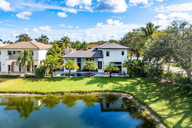 rear view of house featuring a water view, a patio area, stucco siding, and a yard