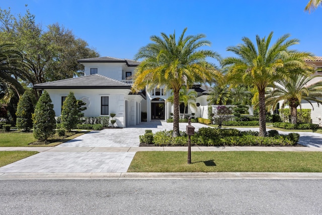 mediterranean / spanish-style house featuring a front yard, decorative driveway, and stucco siding