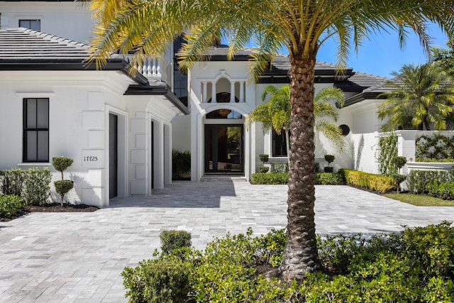 exterior space featuring driveway, a tile roof, and stucco siding