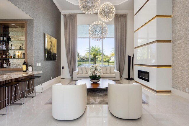 interior space with a towering ceiling, vanity, a notable chandelier, ornamental molding, and a raised ceiling