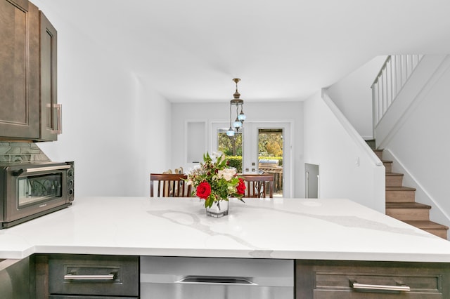 kitchen featuring light stone counters, dark brown cabinets, hanging light fixtures, and french doors