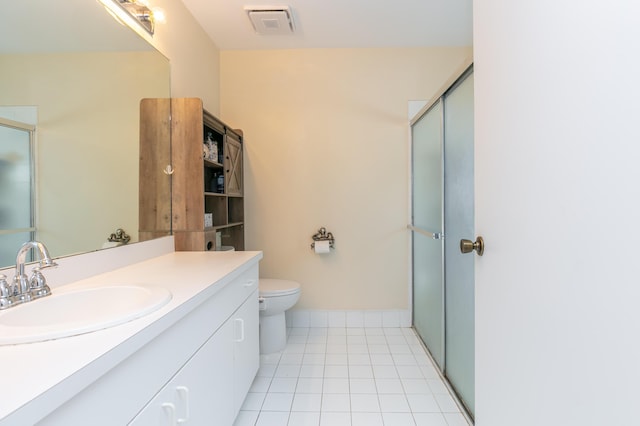 bathroom featuring tile patterned floors, vanity, a shower with shower door, and toilet