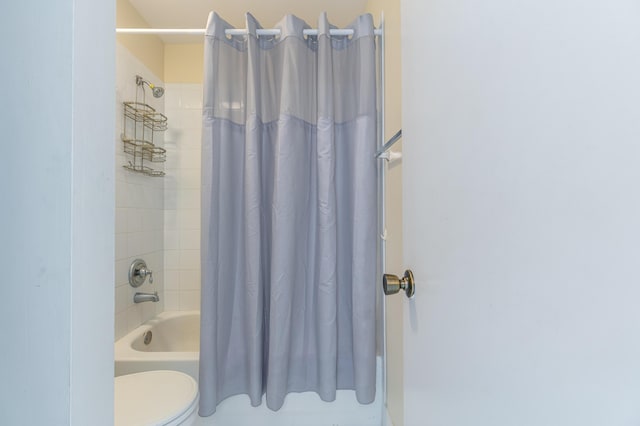 bathroom featuring shower / tub combo and toilet