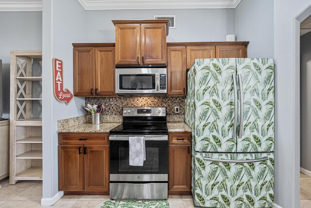 kitchen with appliances with stainless steel finishes, tasteful backsplash, light stone counters, crown molding, and light tile patterned floors