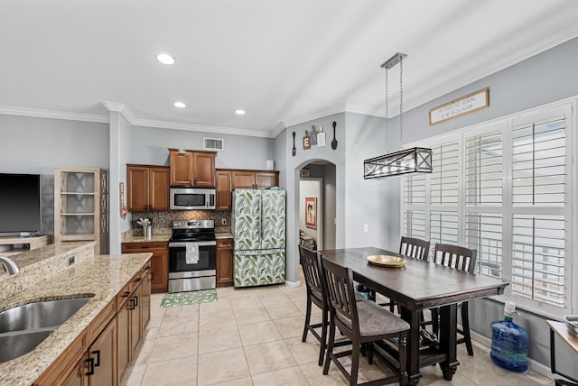 kitchen with tasteful backsplash, stainless steel appliances, sink, light tile patterned floors, and decorative light fixtures