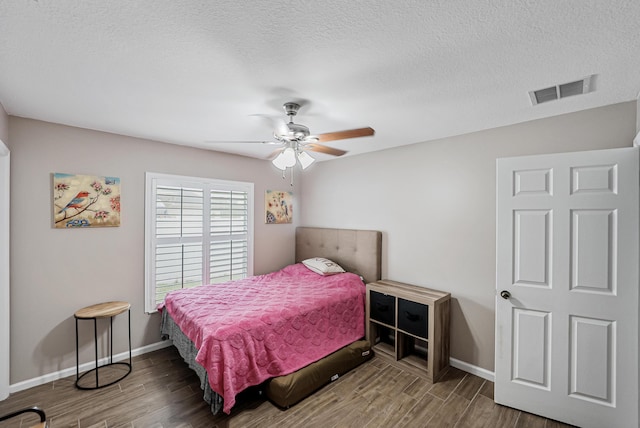 bedroom featuring ceiling fan, dark wood-type flooring, and a textured ceiling