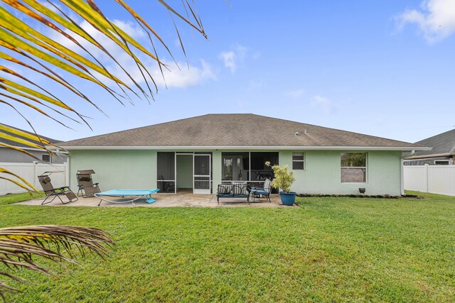 rear view of house with a sunroom, a yard, and a patio