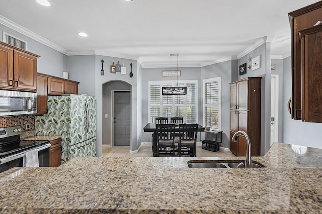 kitchen with sink, hanging light fixtures, light tile patterned floors, ornamental molding, and stainless steel appliances