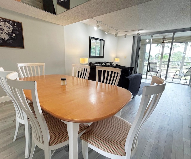 dining space featuring ceiling fan, rail lighting, a textured ceiling, and hardwood / wood-style flooring