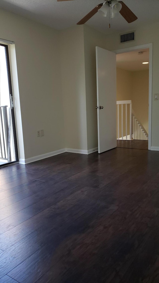 empty room with ceiling fan, a textured ceiling, and dark wood-type flooring