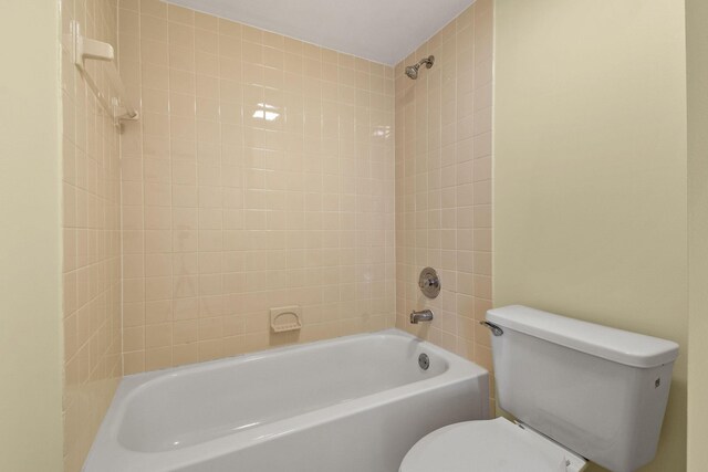 bathroom with tiled shower / bath combo and toilet