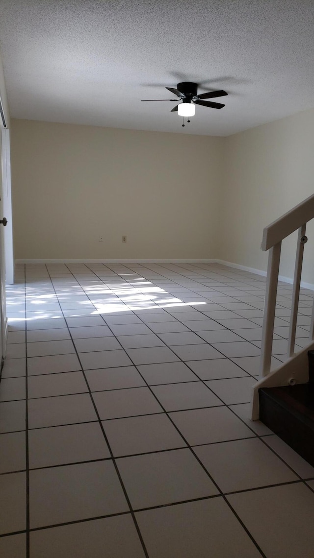 spare room with ceiling fan, light tile patterned floors, and a textured ceiling