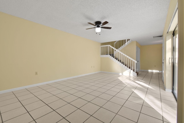 spare room with a textured ceiling, ceiling fan, and light tile patterned flooring