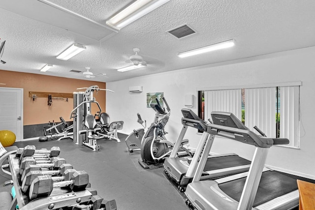 exercise room with ceiling fan, a wall mounted air conditioner, and a textured ceiling