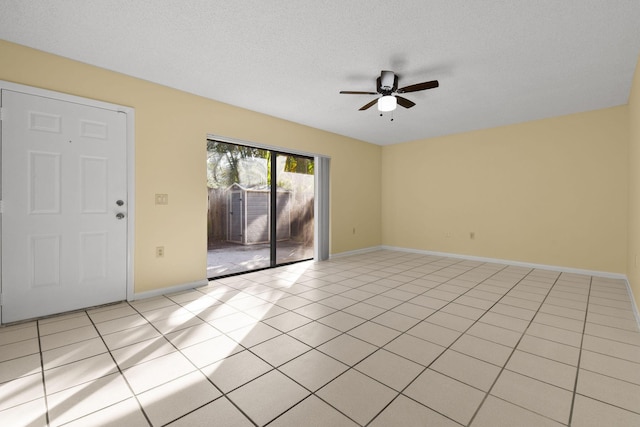 empty room with ceiling fan, a textured ceiling, and light tile patterned floors