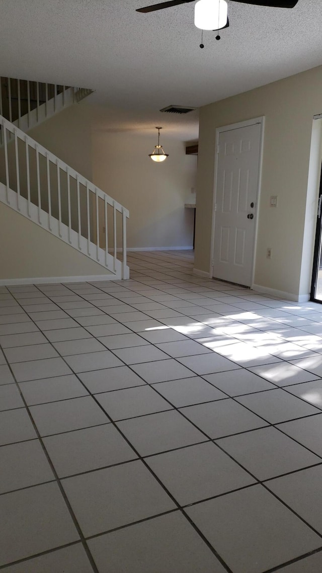 unfurnished room featuring ceiling fan, light tile patterned floors, and a textured ceiling