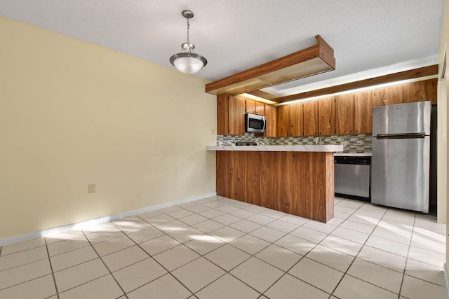 kitchen with appliances with stainless steel finishes, kitchen peninsula, decorative backsplash, and light tile patterned floors