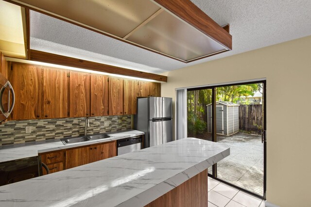 kitchen featuring sink, backsplash, stainless steel appliances, and light tile patterned flooring