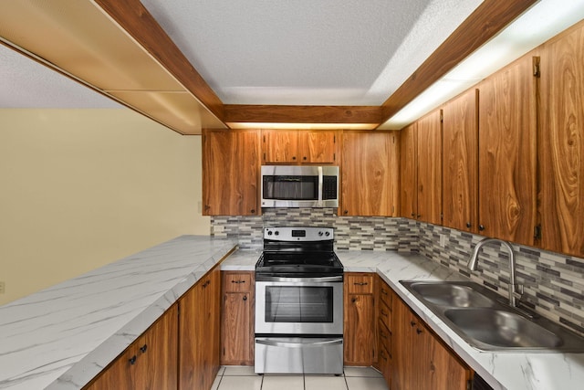 kitchen with sink, appliances with stainless steel finishes, tasteful backsplash, a textured ceiling, and light tile patterned flooring