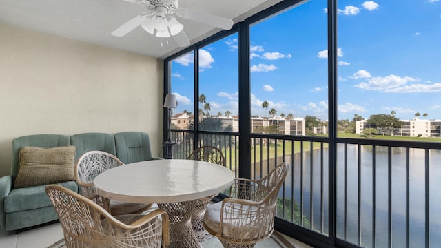 sunroom / solarium with ceiling fan and a water view