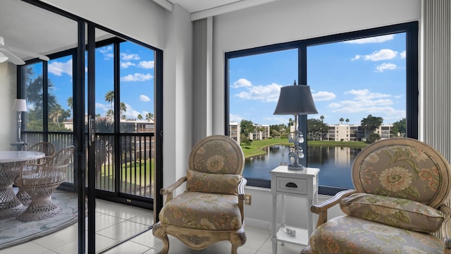 living area with a wealth of natural light, a water view, and light tile patterned floors