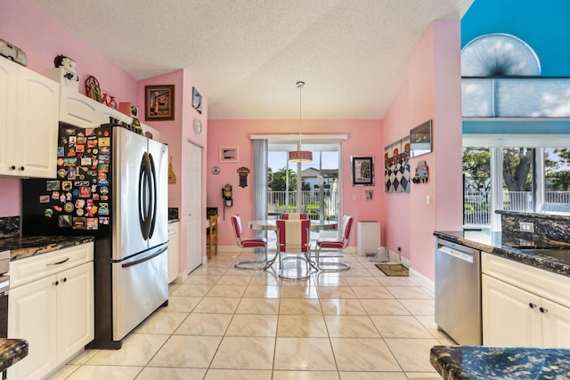 kitchen with stainless steel appliances, white cabinetry, dark stone countertops, and light tile patterned flooring