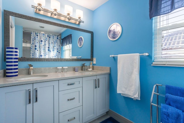 full bathroom featuring a wealth of natural light, double vanity, and a sink