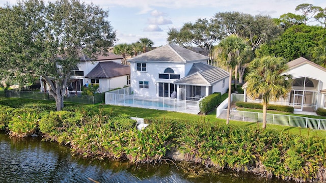 rear view of house featuring a water view, a fenced backyard, a sunroom, and stucco siding