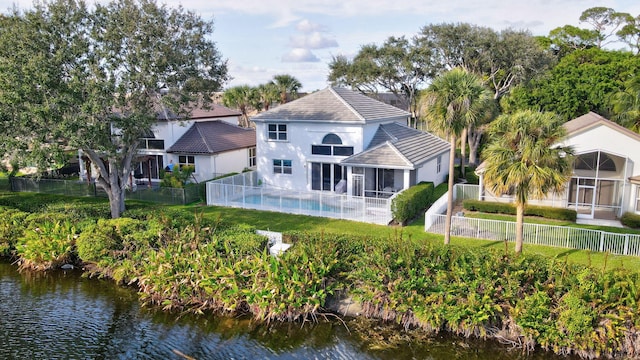 rear view of property with a water view, a fenced in pool, and a sunroom