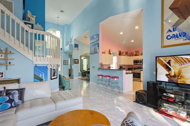 tiled living room featuring a towering ceiling and a chandelier