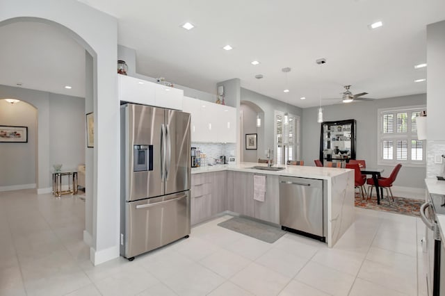 kitchen with white cabinetry, sink, ceiling fan, stainless steel appliances, and kitchen peninsula