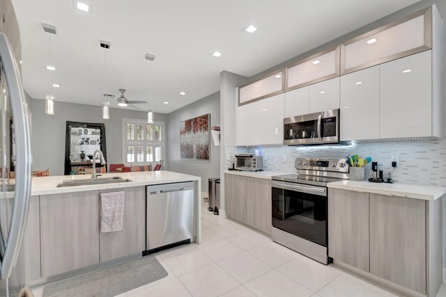 kitchen featuring backsplash, sink, ceiling fan, decorative light fixtures, and stainless steel appliances