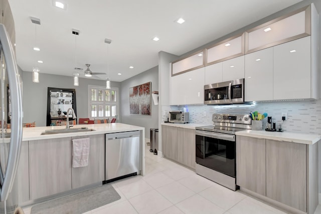 kitchen with light tile patterned flooring, sink, appliances with stainless steel finishes, pendant lighting, and backsplash