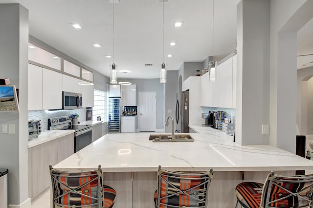 kitchen with appliances with stainless steel finishes, sink, a breakfast bar area, hanging light fixtures, and light stone counters