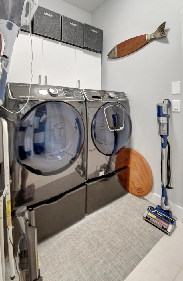 laundry room featuring cabinets, washing machine and dryer, and tile patterned flooring