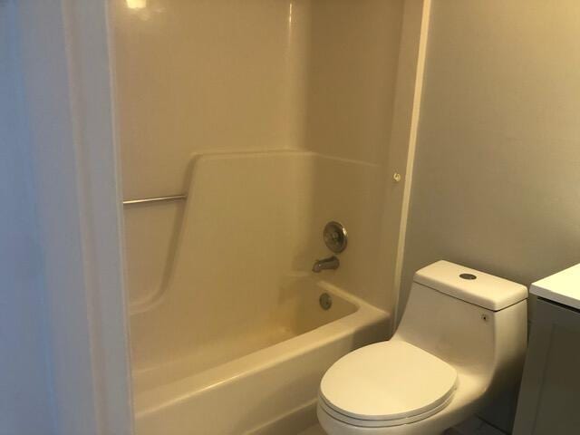 full bathroom featuring washtub / shower combination, vanity, and toilet