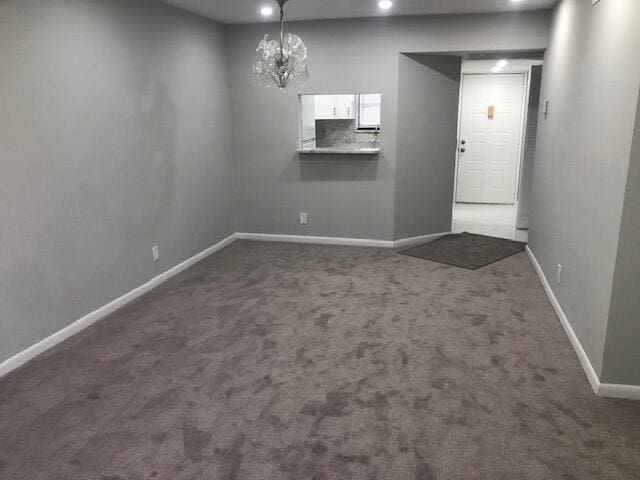 unfurnished dining area with dark carpet and a notable chandelier