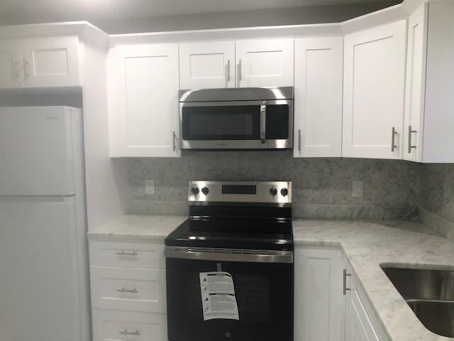 kitchen featuring white cabinets, decorative backsplash, and stainless steel appliances