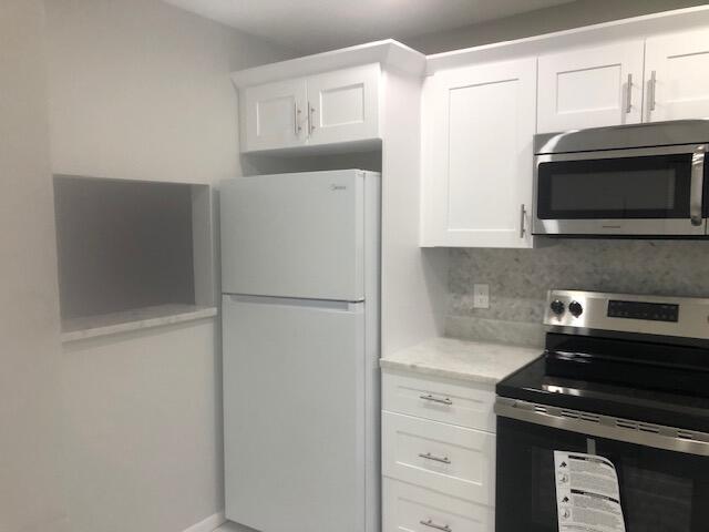 kitchen featuring tasteful backsplash, white cabinets, and appliances with stainless steel finishes