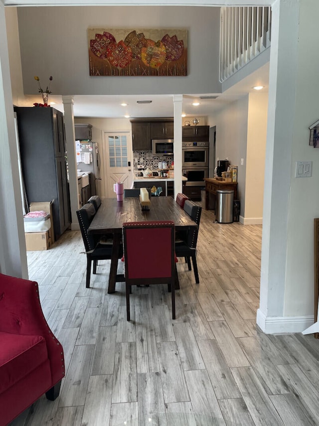 dining space with light wood-type flooring and a high ceiling