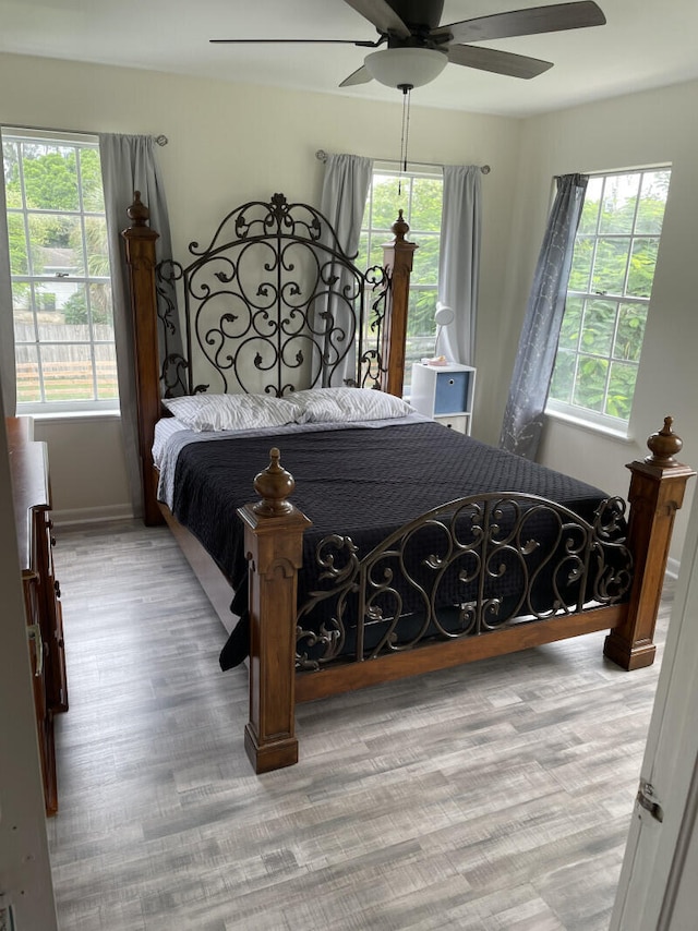 bedroom with multiple windows, ceiling fan, and light hardwood / wood-style floors