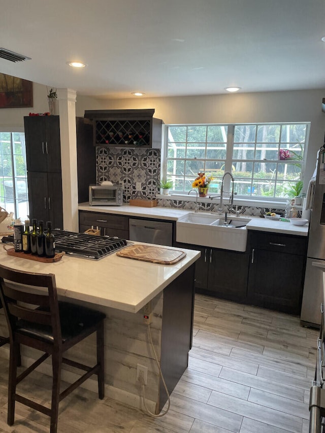 kitchen featuring decorative backsplash, appliances with stainless steel finishes, a wealth of natural light, sink, and a breakfast bar area