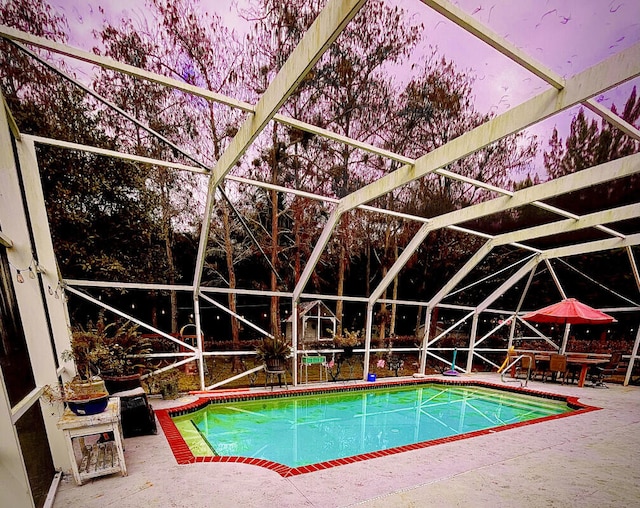 pool at dusk with a patio and a lanai