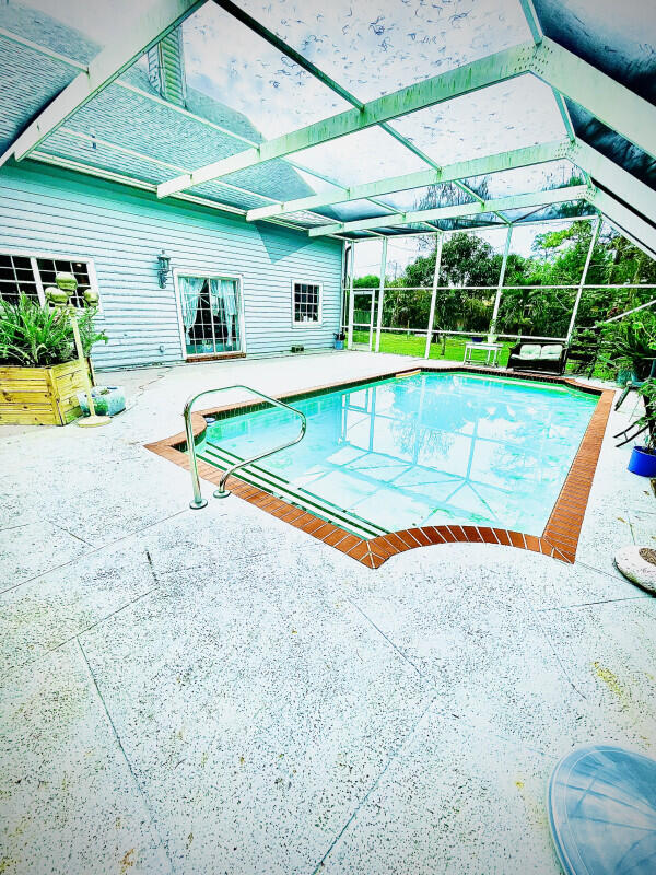 view of pool with glass enclosure and a patio area