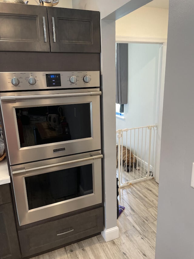 kitchen with dark brown cabinets, light hardwood / wood-style floors, and double oven