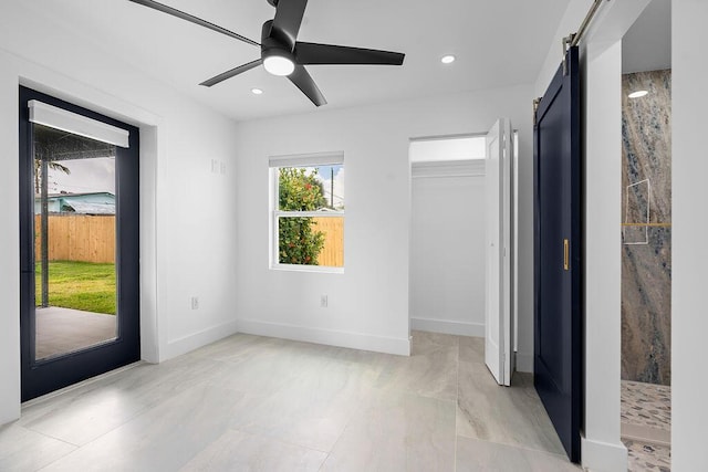 interior space with a barn door, ceiling fan, and a closet