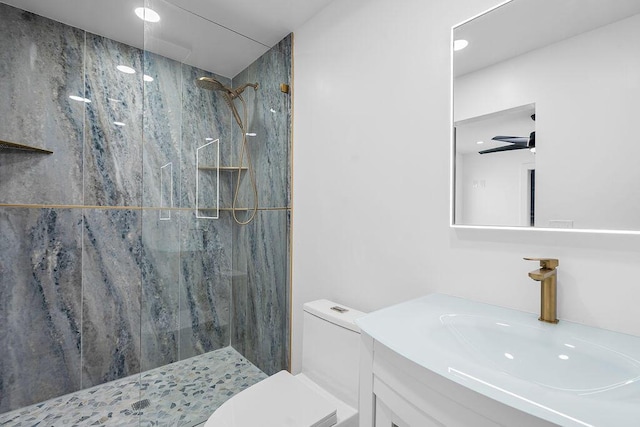 bathroom with tiled shower, ceiling fan, vanity, and toilet