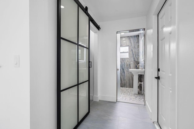 hall featuring light tile patterned floors and a barn door